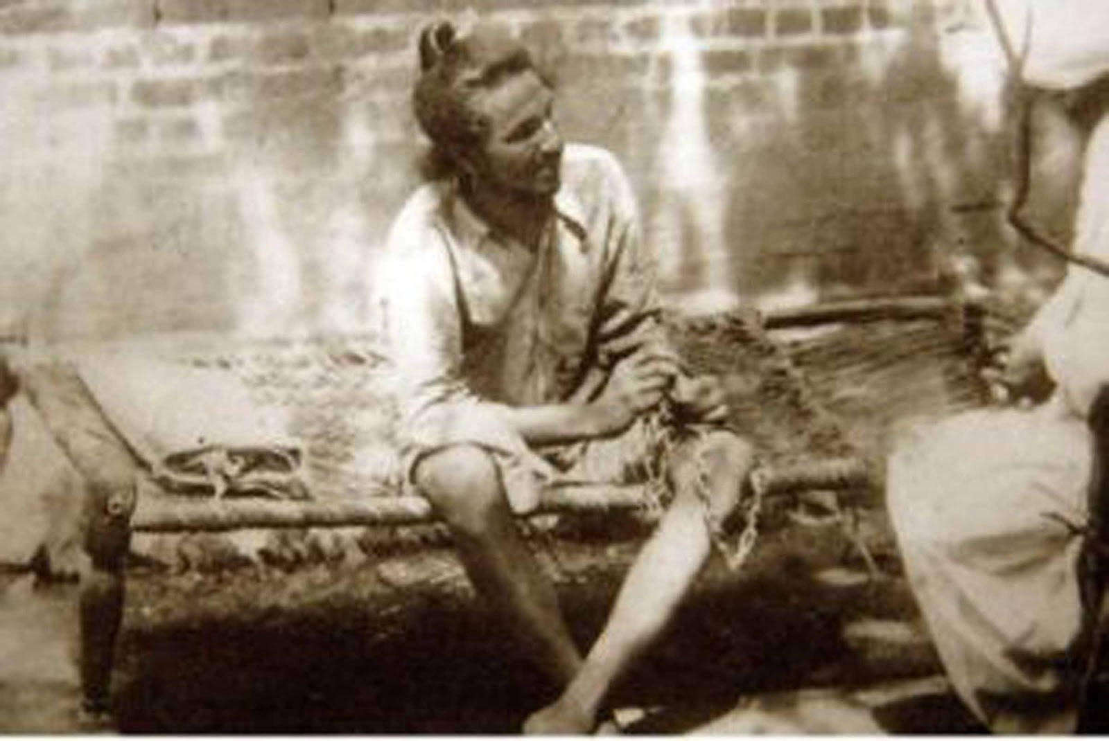 Bhagat Singh in police custody, sitting on a cot with open hair